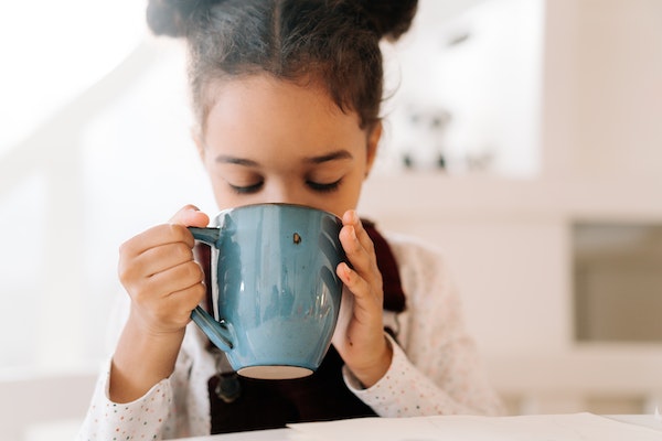child drinking hot chocolate to represent keeping your children warm