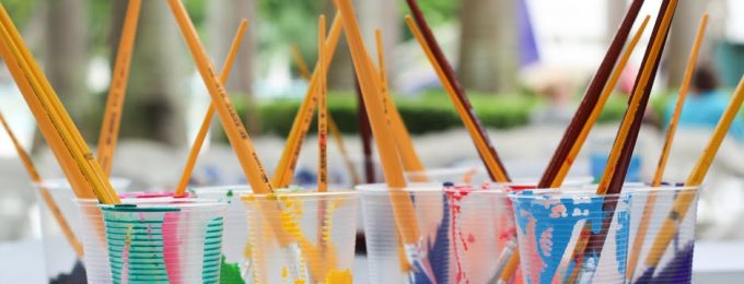 A row of cups filled with different coloured paint