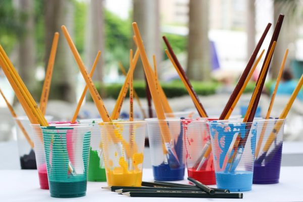 A row of cups filled with different coloured paint