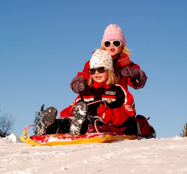 Two girls on a sled on the snow