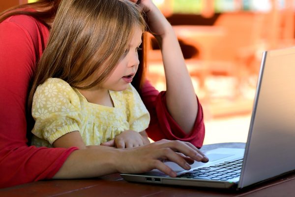 A little girl on the computer with her mother