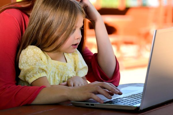 A mum and daughter looking at a laptop screen