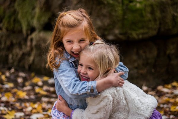 Two little girls hugging and laughing outside