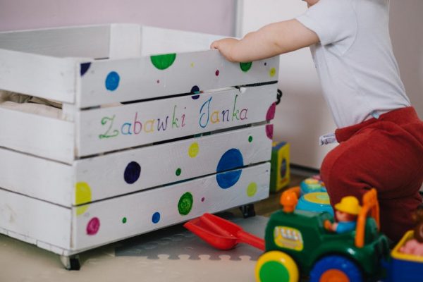 A little boy reaching into a toy box