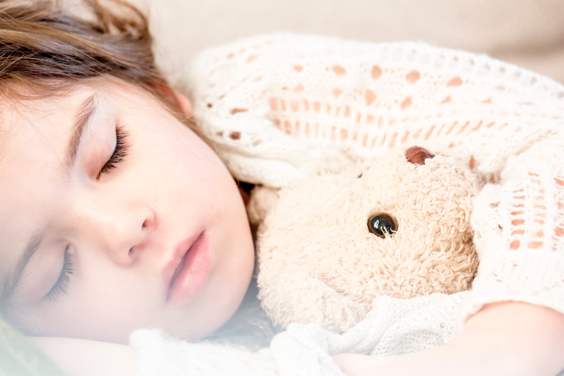 A little girl sleeping with a teddy