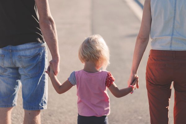 A little girl holding her parents' hands