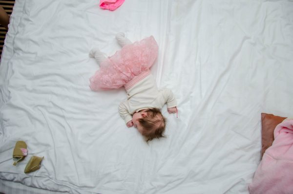 A baby lying face down on a bed sleeping