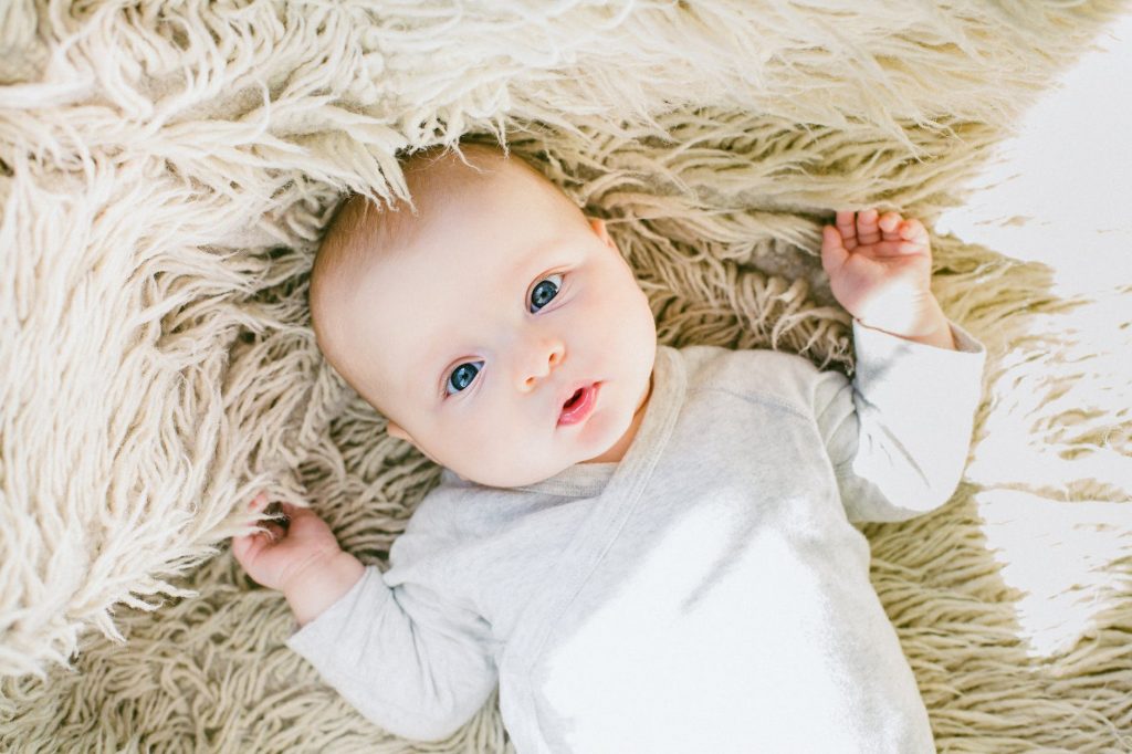 A baby lying down and looking up at the camera