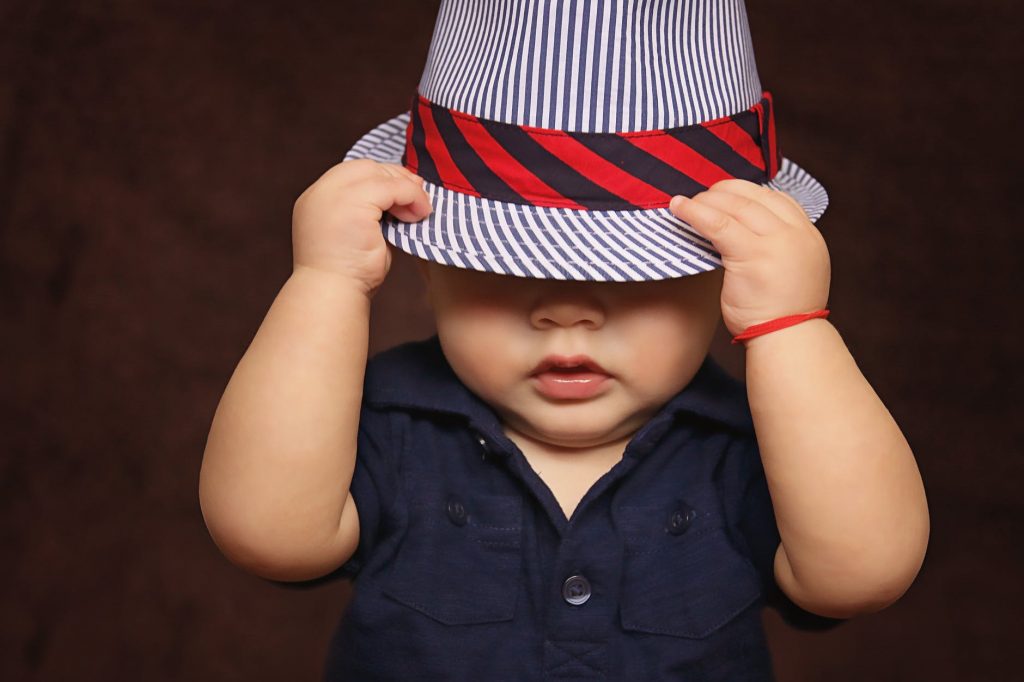 A young boy pulling a hat over his face