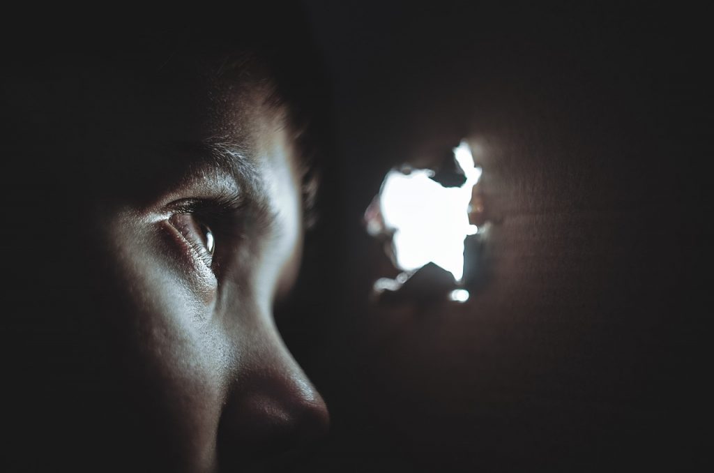 A child hiding and peering through a hole 