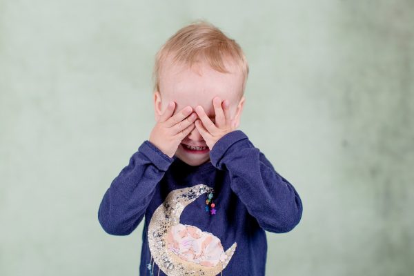 a little boy covering his eyes with his hands