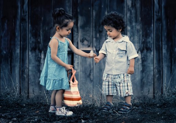 A little boy giving a little girl a flower a little boy holding his mother's face to represent how to teach your child kindness