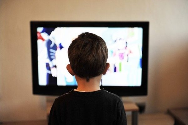 A young boy staring at a tv screen