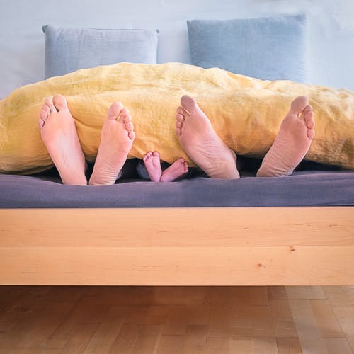 Parents and child's feet sticking out of the bed covers