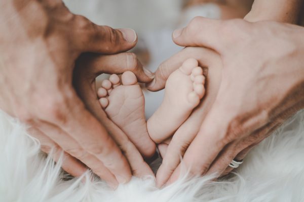 Parents hands making a heart around baby feet