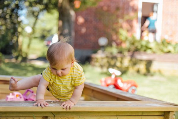 a child in a sand box to represent how to make a sensory bin