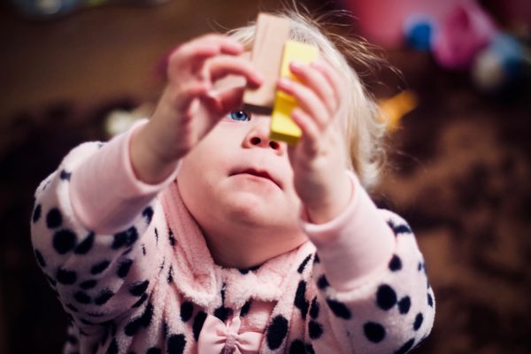 a little girl playing with two building blocks to represent learning at home