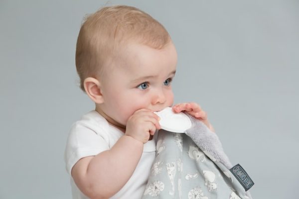 Teething baby chewing on grey cloth