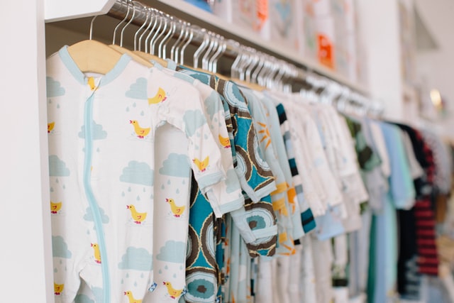 A rail full of baby clothes to represent how to teach your child about charity by teaching them about donating old clothes