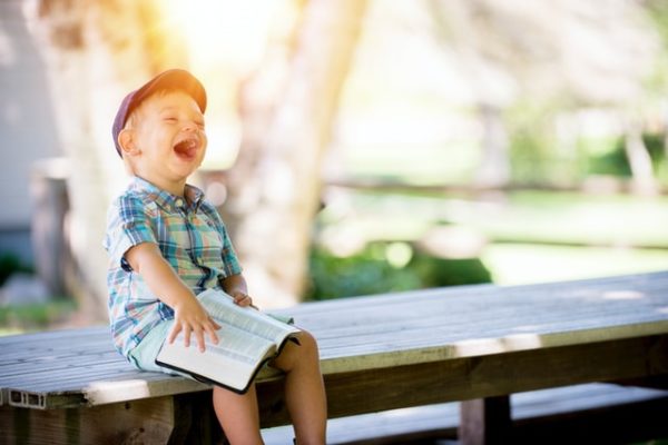 child laughing whilst reading to represent creating a daily routine for toddlers