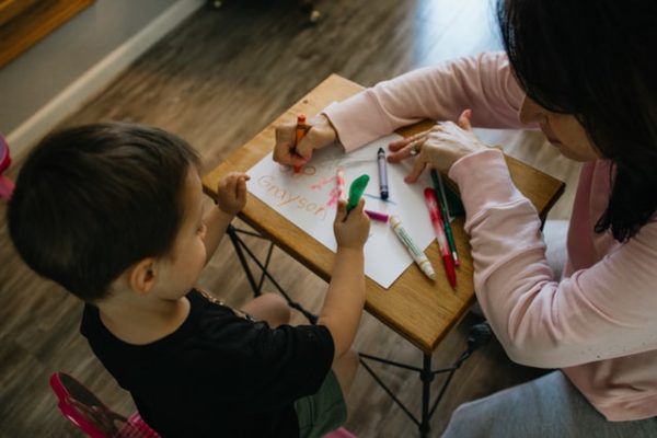 A carer drawing with a child to represent Why Join a Schoolhouse Day Nursery