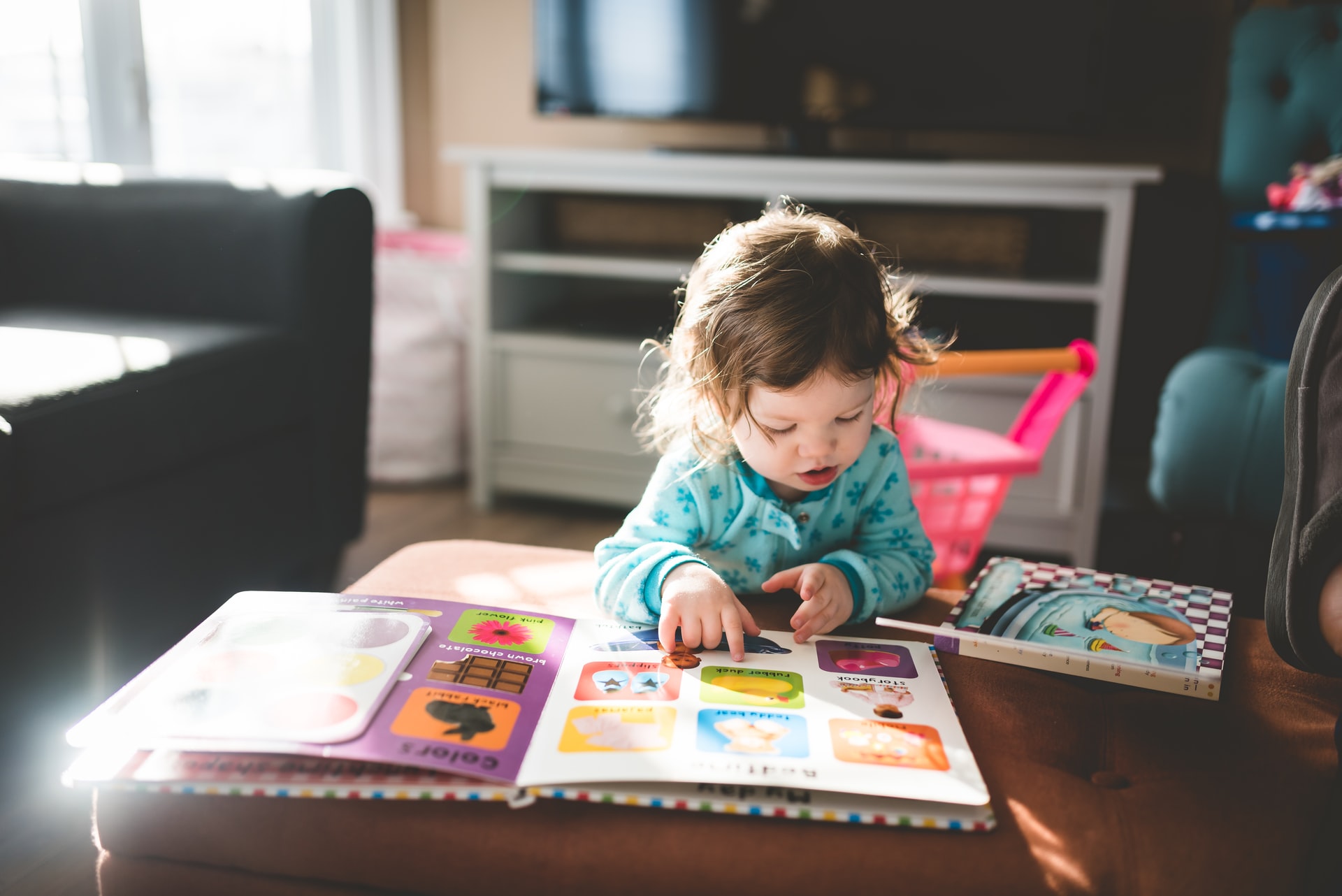 A toddler reading a book to represent creating a routine for toddlers at nursery