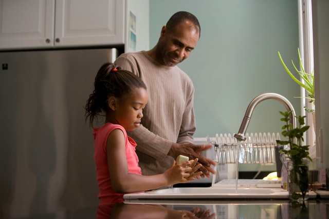 A child and parent washing up to represent how young children can help in the kitchen