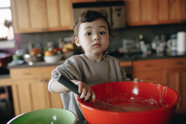 a child using a whisk to represent how young children can help in the kitchen