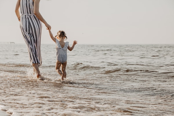 Mother and daughter paddling at the beach to represent family days out in Wales