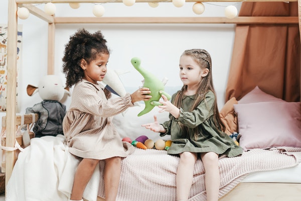 Two children playing with a toy dinosaur to represent starting school