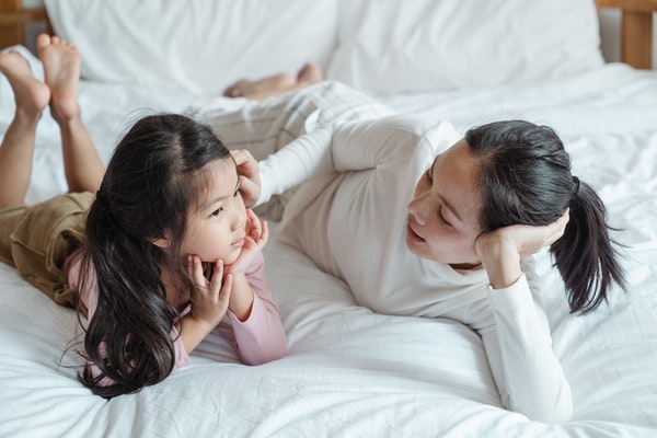 Mother and daughter talking on their bed to represent starting school