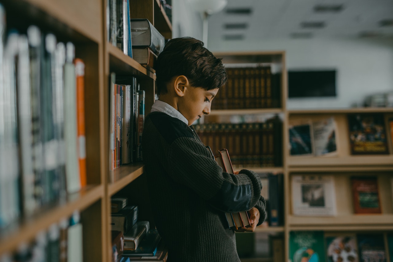 boy stood in a library looking anxious to represent back-to-school anxiety