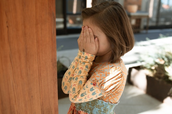 A child hiding behind her hands to represent back-to-school anxiety