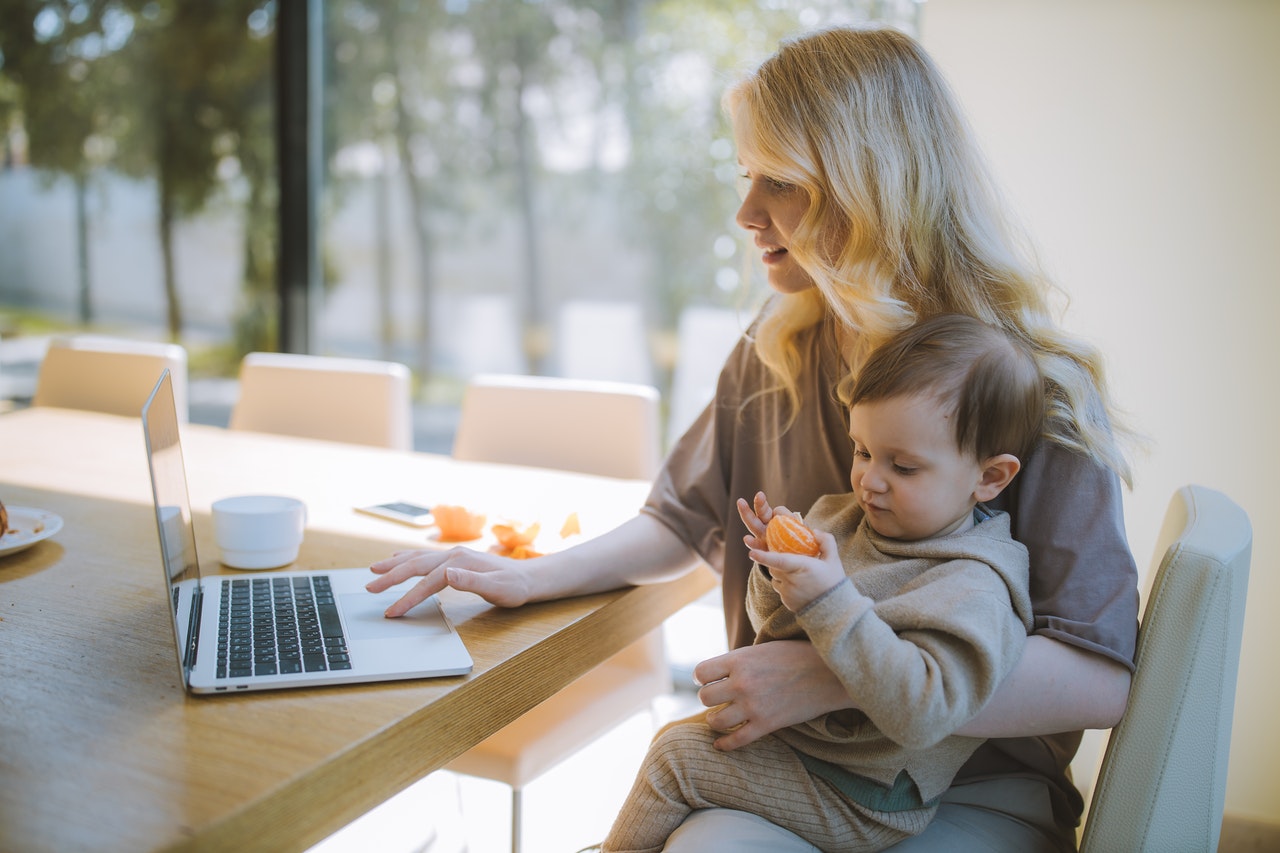 A woman working from home holding their toddler on their lap to represent how to switch off after work as a parent