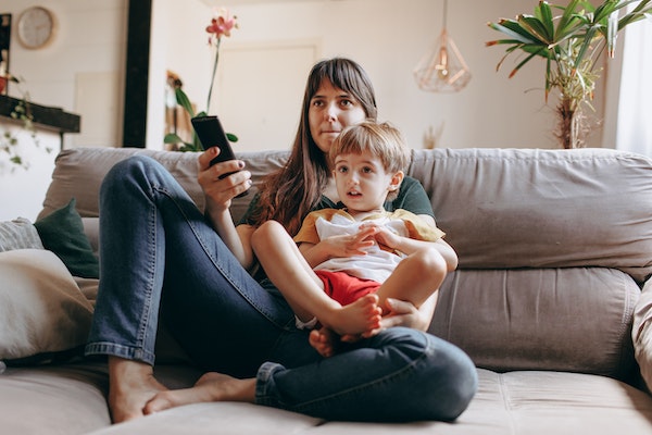 A woman and son watching TV to represent how to switch off after work as a parent