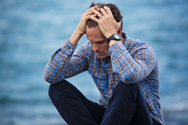 Stressed man holding his head to represent how to prioritise self-care as a parent