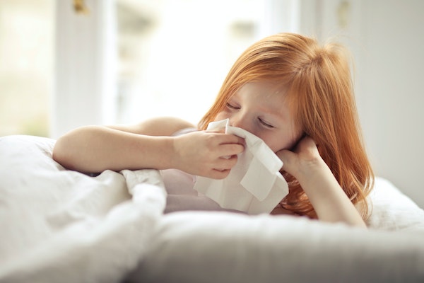 Child blowing her nose to represent childhood illnesses