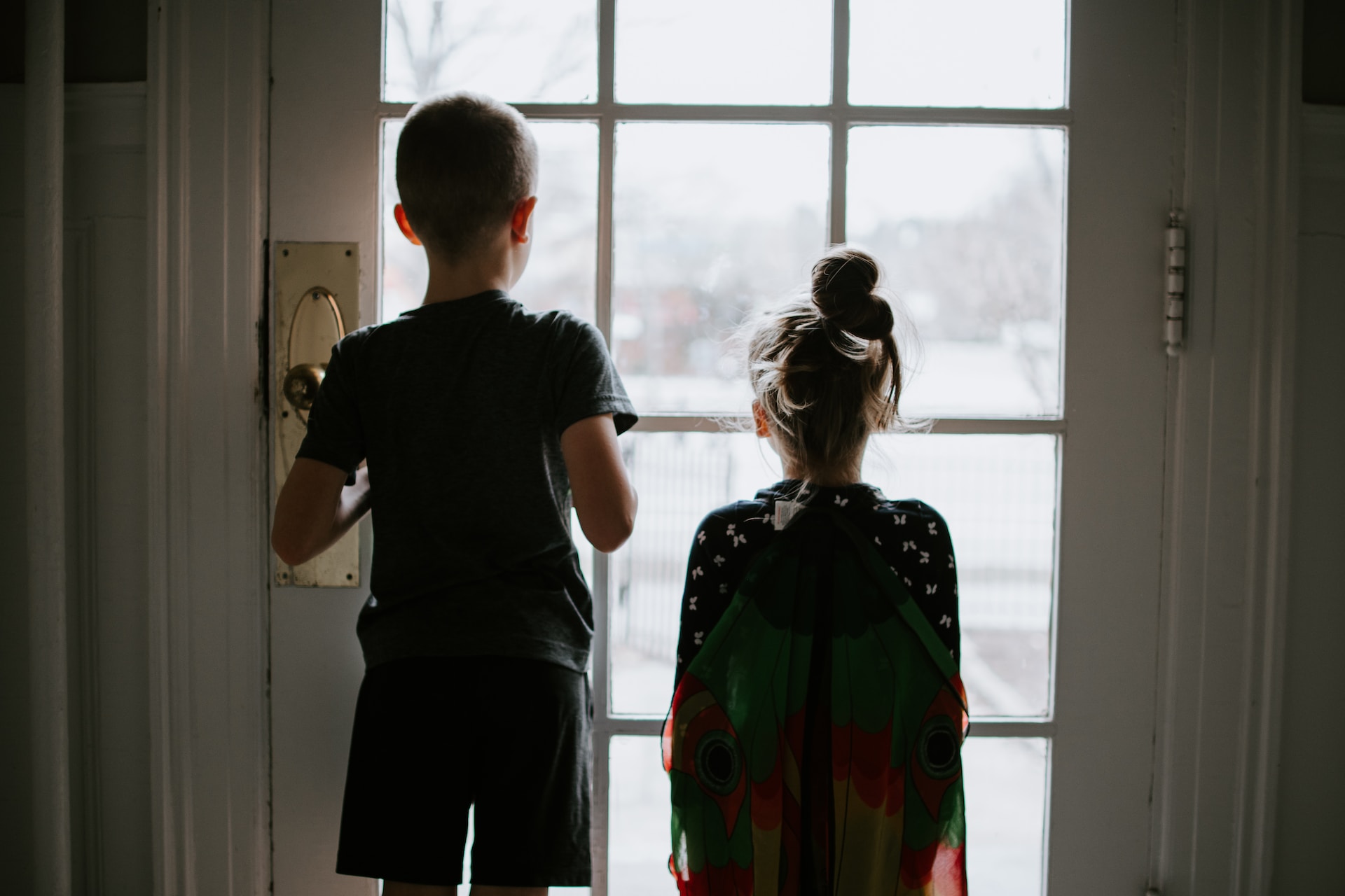 two children looking outside to represent rainy day activities