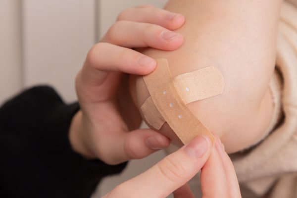 a parent putting a plaster on a child